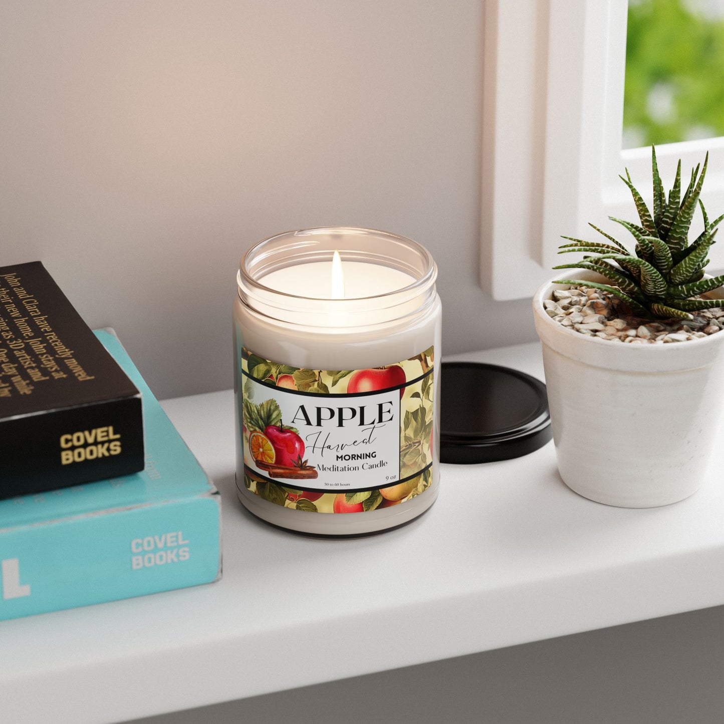 Candle labeled 'Apple' on a shelf with books and a plant