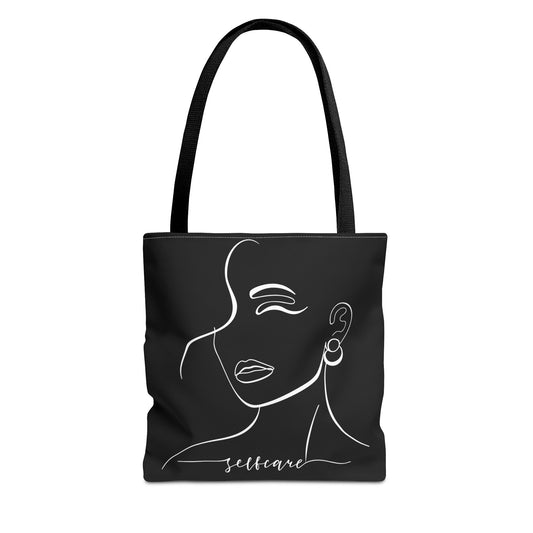 Black tote bag with a white line drawing of a woman's face and the word 'selfcare'.