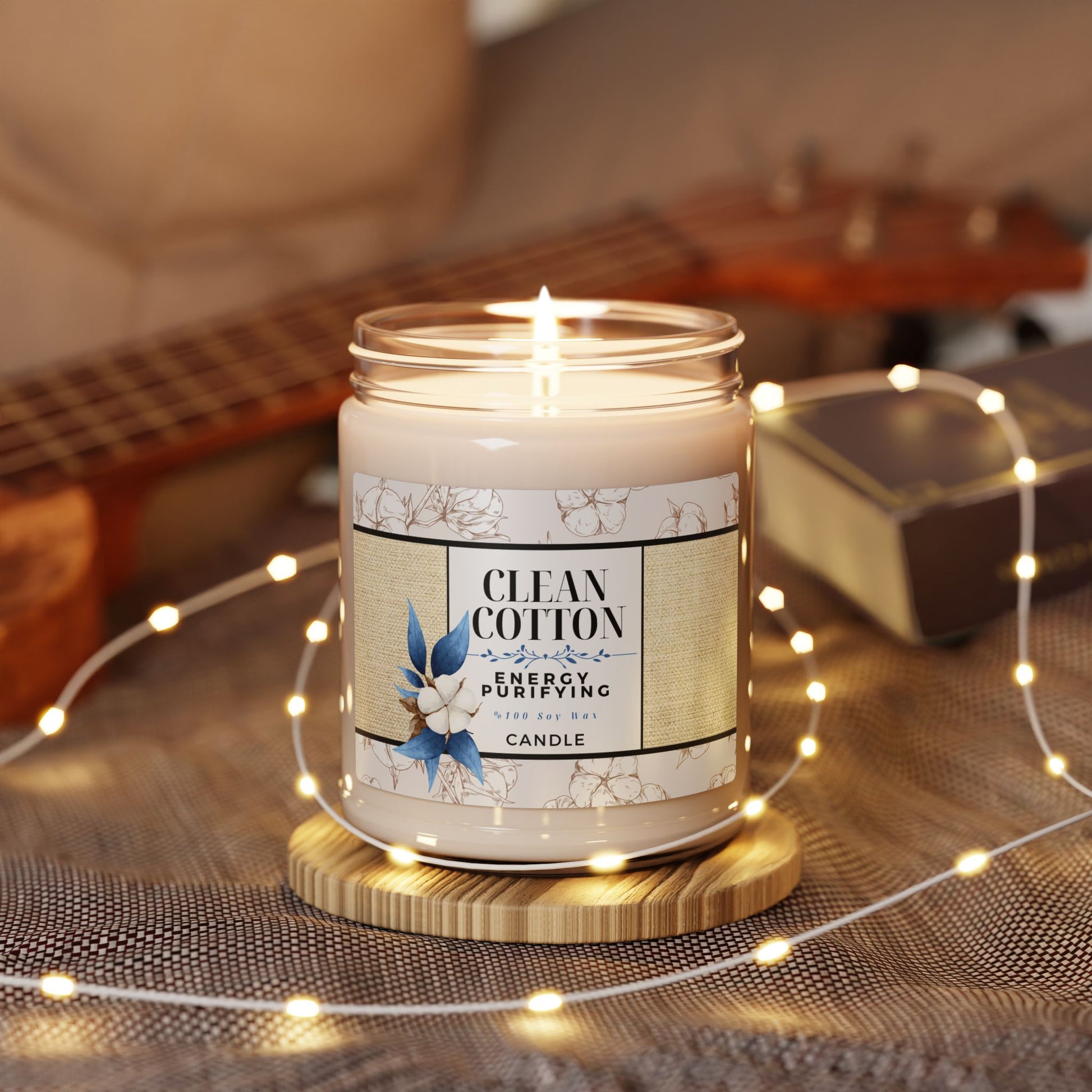 Candle labeled 'Clean Cotton' with a guitar and string lights in the background