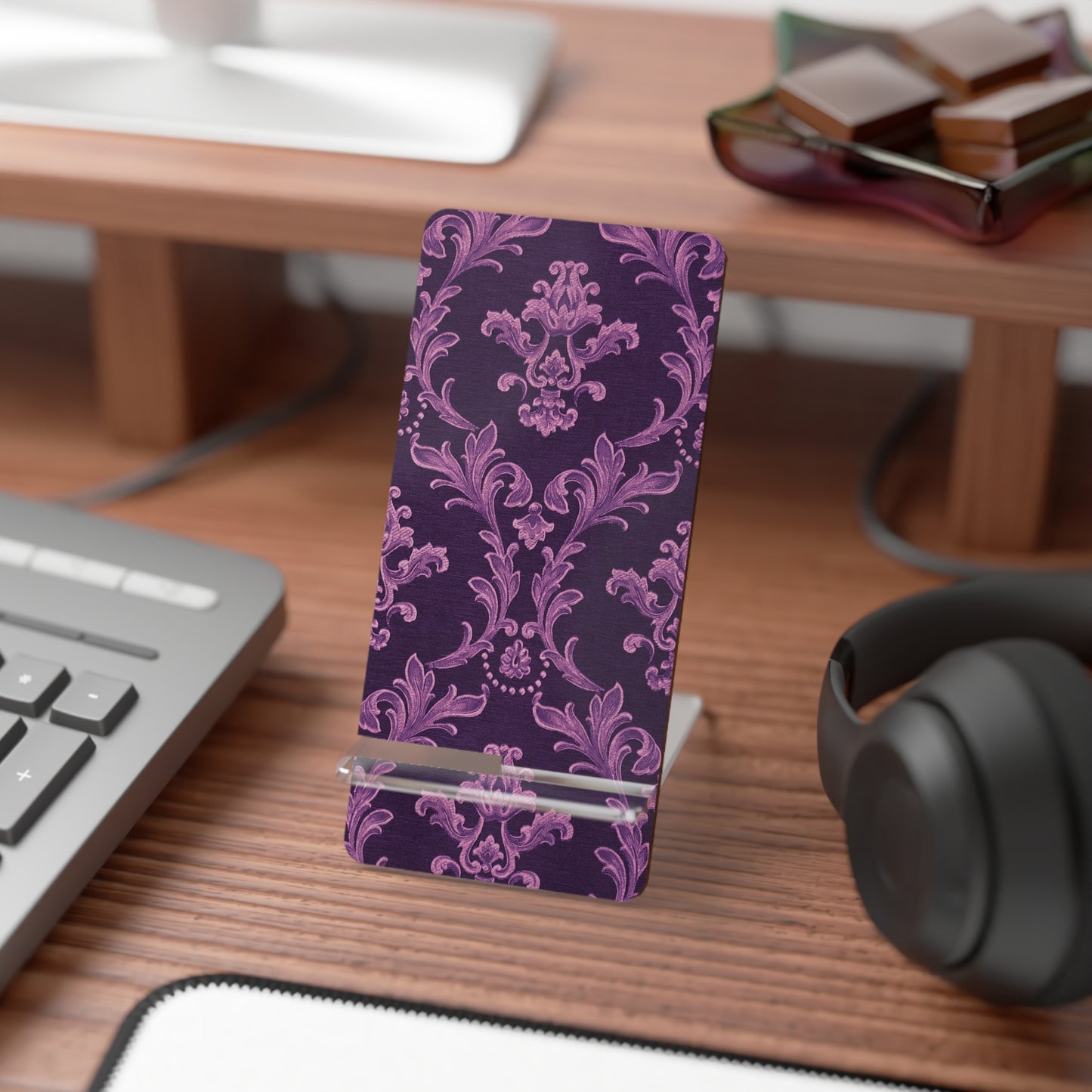 Purple patterned phone stand on a desk with a keyboard and headphones