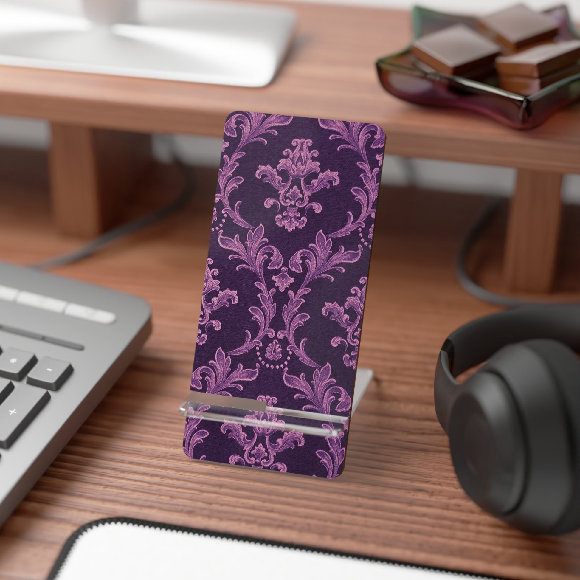Purple patterned phone stand on a desk with a keyboard and headphones