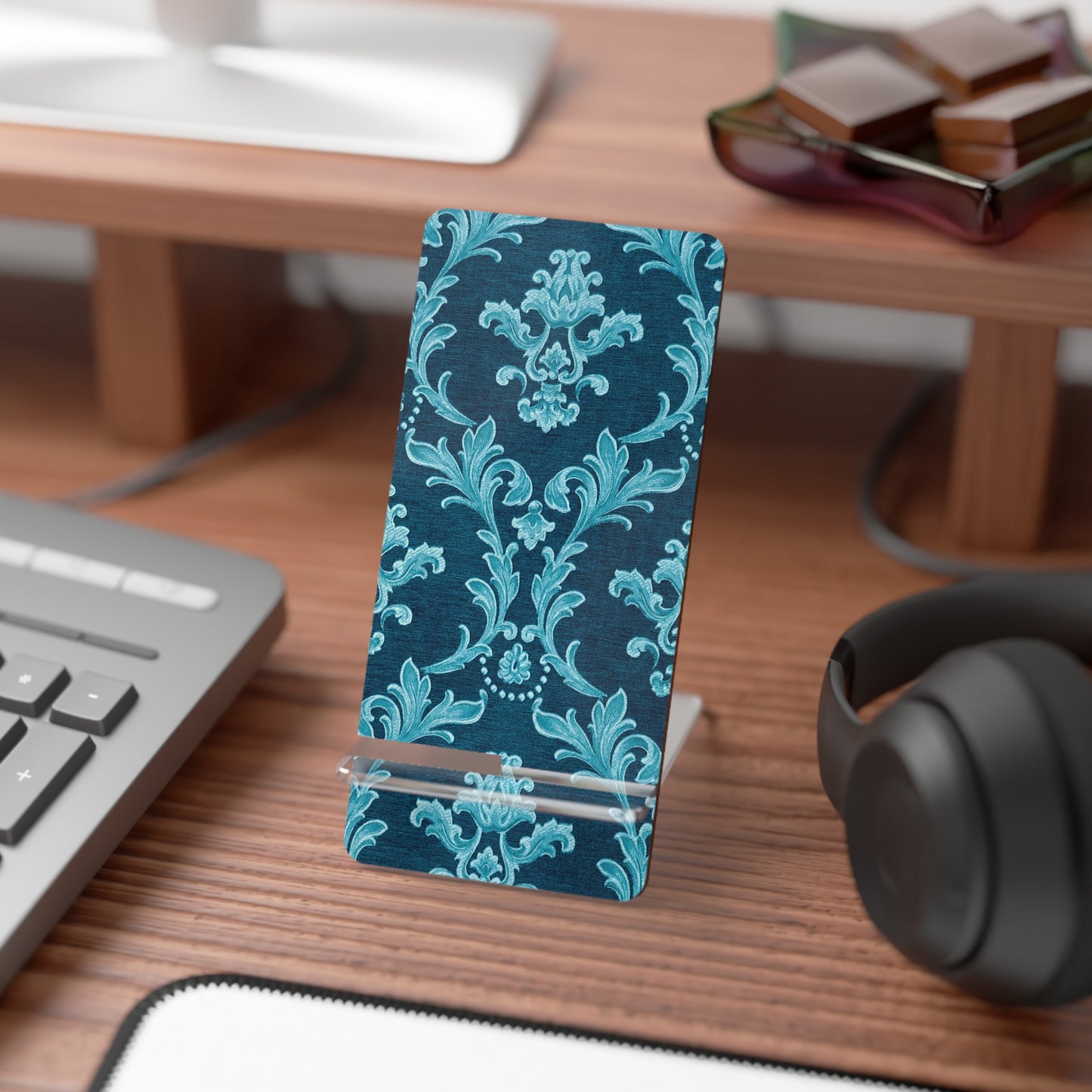 Blue floral patterned phone stand on a desk with keyboard, mouse, and headphones.