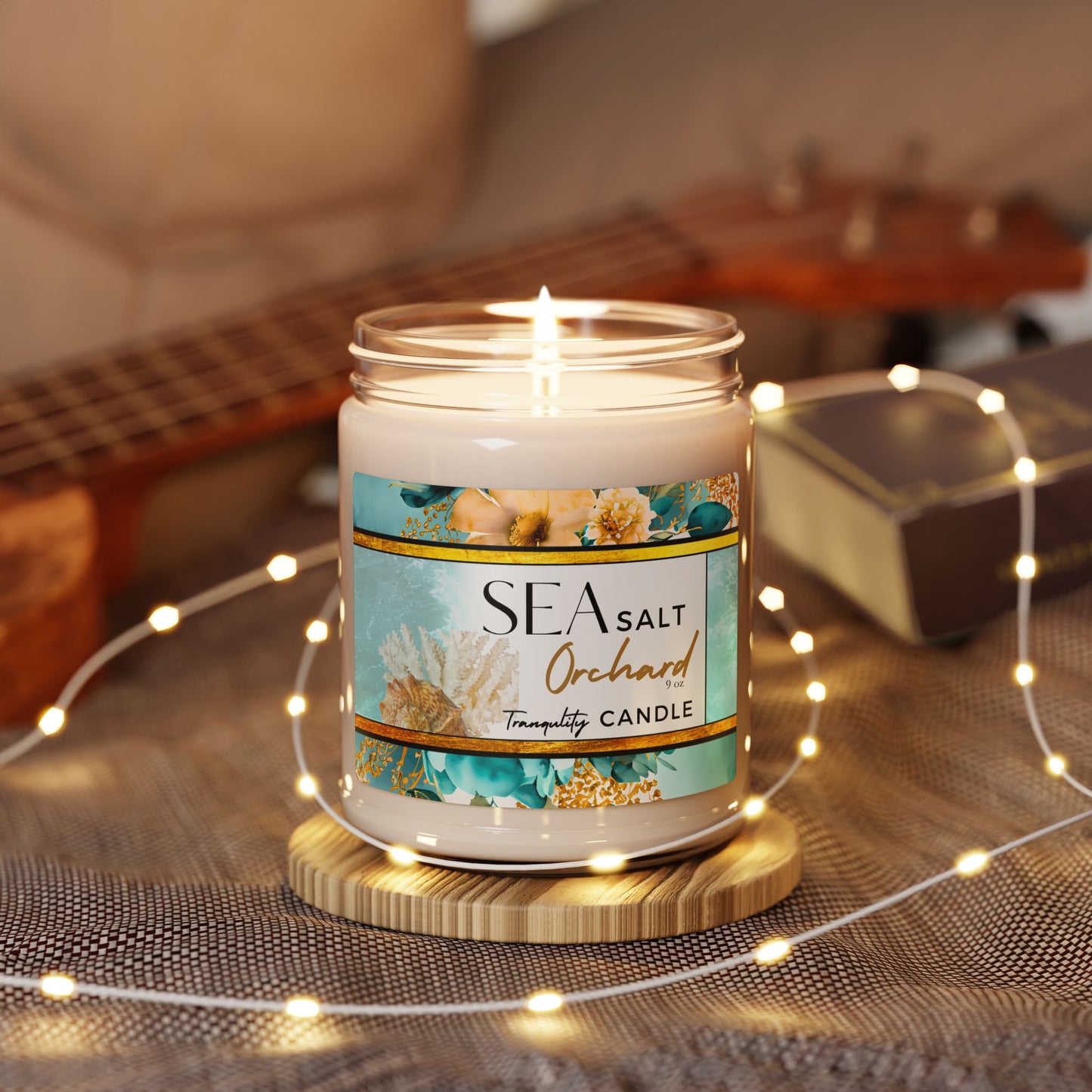 Lit candle in a jar with a 'Sea Salt Orchard' label on a wooden coaster, surrounded by string lights.